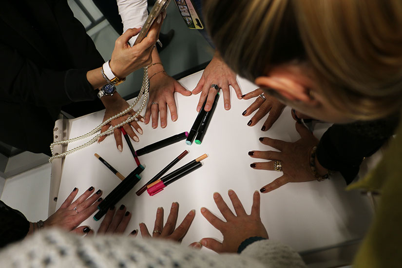 Une équipe de 6 personnes ont leur mains posées sur une feuille blanche avec des stylos autour.