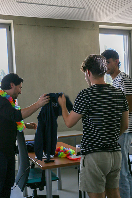 Professeur distribue des sweat-shirt à deux étudiants
